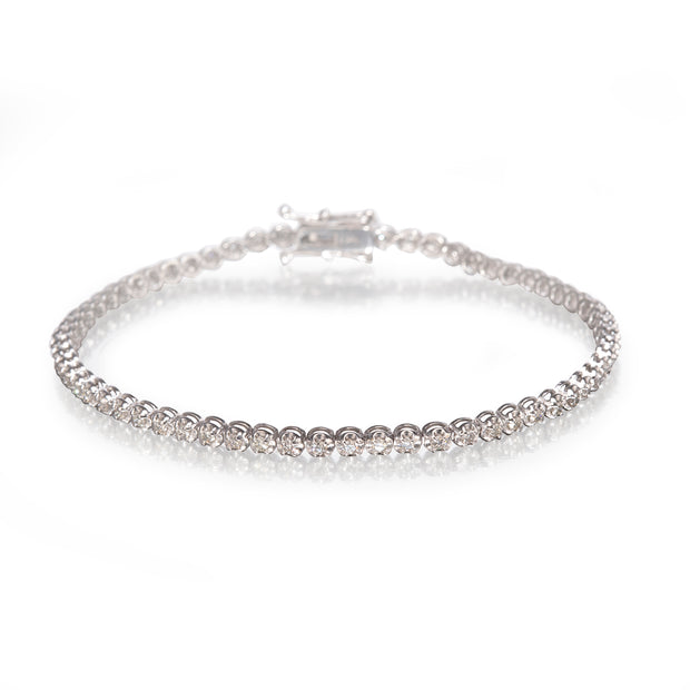A white gold tennis bracelet with a continuous row of clear round-cut stones, displayed on a clean white reflective surface.