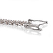 Close-up of a white gold tennis bracelet showing the clasp and part of the chain on a white reflective surface.