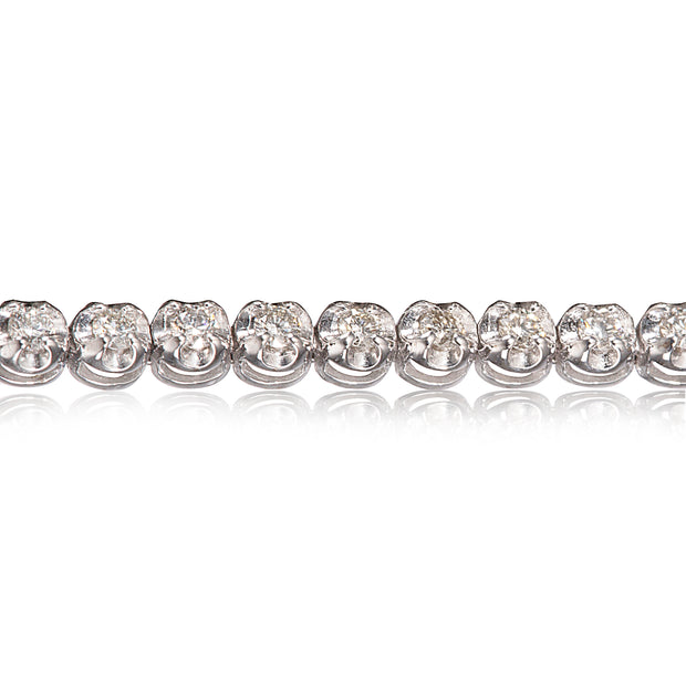 A close-up of a diamond tennis bracelet on a clean white background with a soft reflection below.