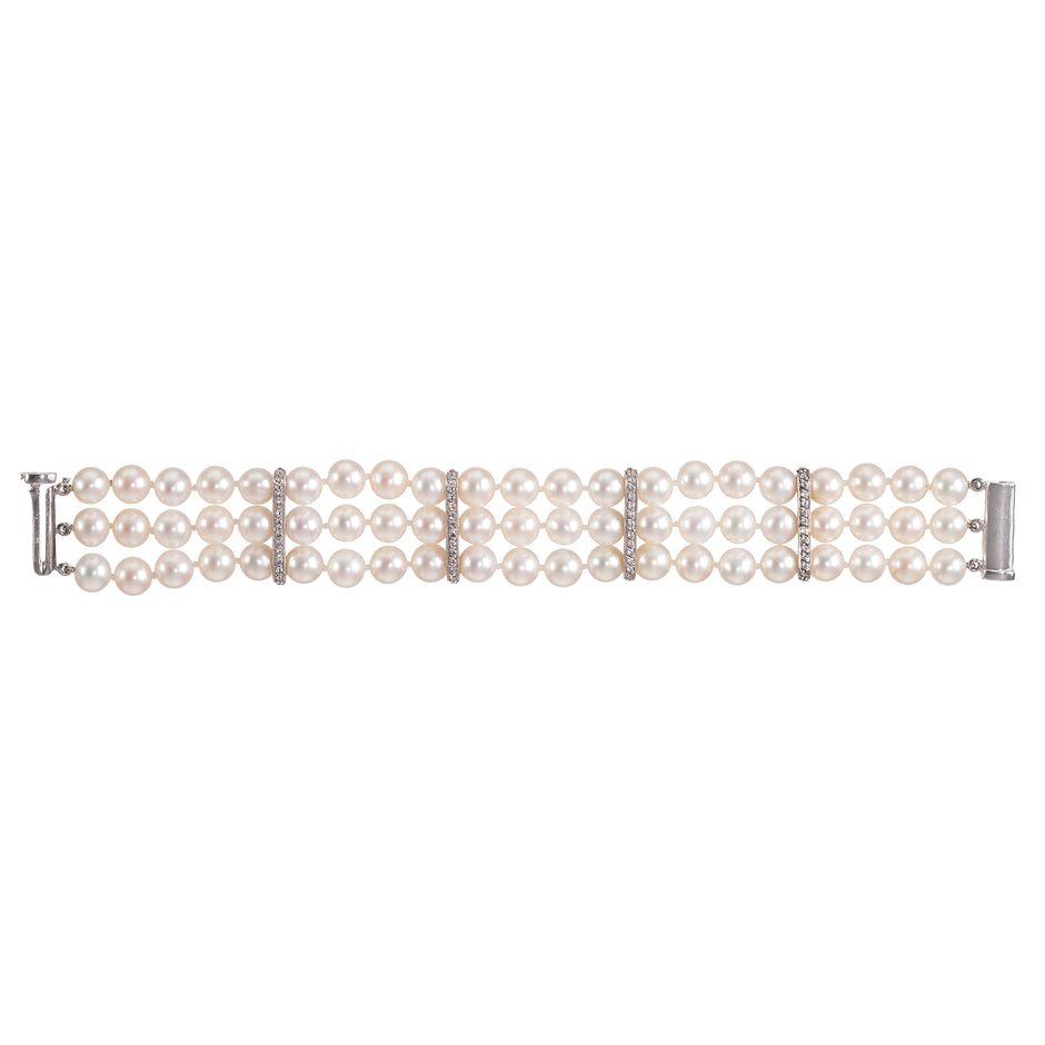 A white gold triple-row pearl bracelet with diamond accents between rows, displayed horizontally on a clean white background.