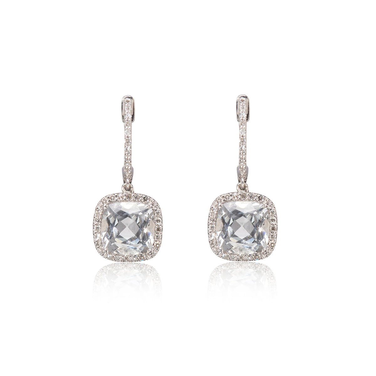 A pair of white gold drop earrings featuring cushion-cut clear gemstones surrounded by small pavé-set stones, shown on a white background with a soft reflection below.