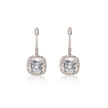 A pair of white gold drop earrings featuring cushion-cut clear gemstones surrounded by small pavé-set stones, shown on a white background with a soft reflection below.