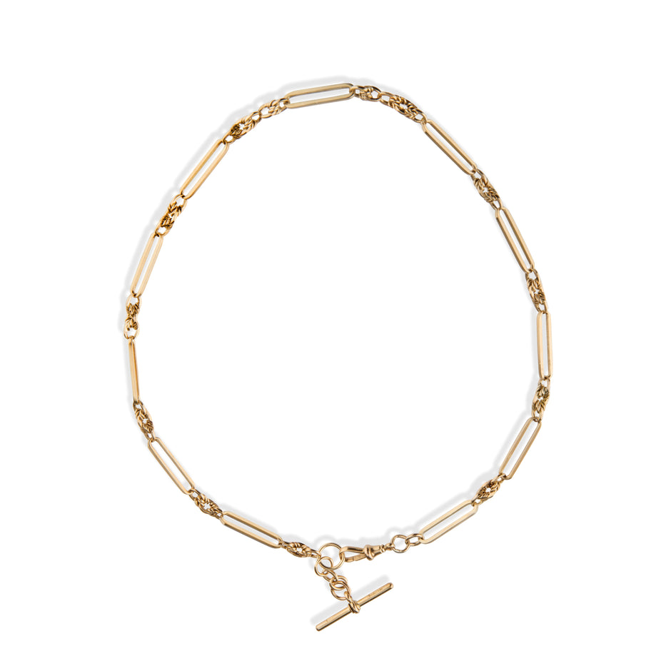 A gold paperclip chain necklace with a toggle clasp, displayed on a clean white background.
