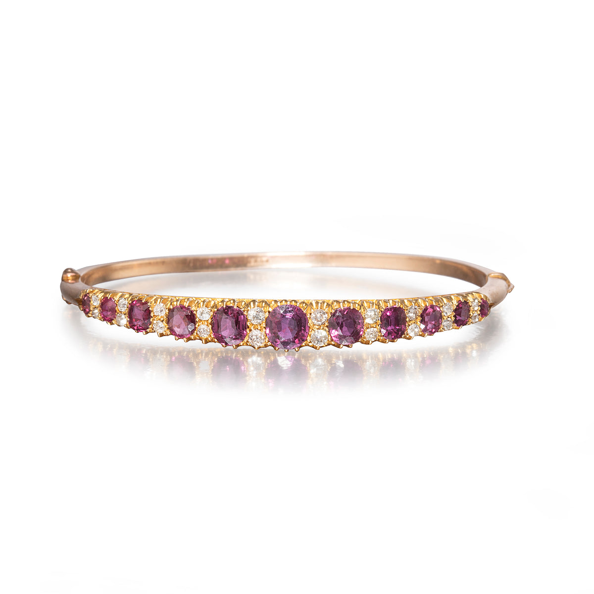 A rose gold bangle bracelet featuring a row of oval purple amethyst gemstones and small clear accent stones, shown on a clean white background with a soft reflection.