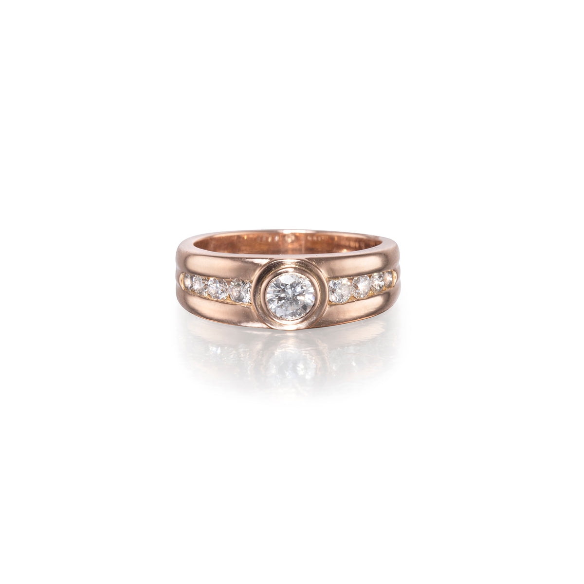 A rose gold ring with a central round-cut diamond and small pavé diamonds on either side, set against a clean white background with a soft reflection.