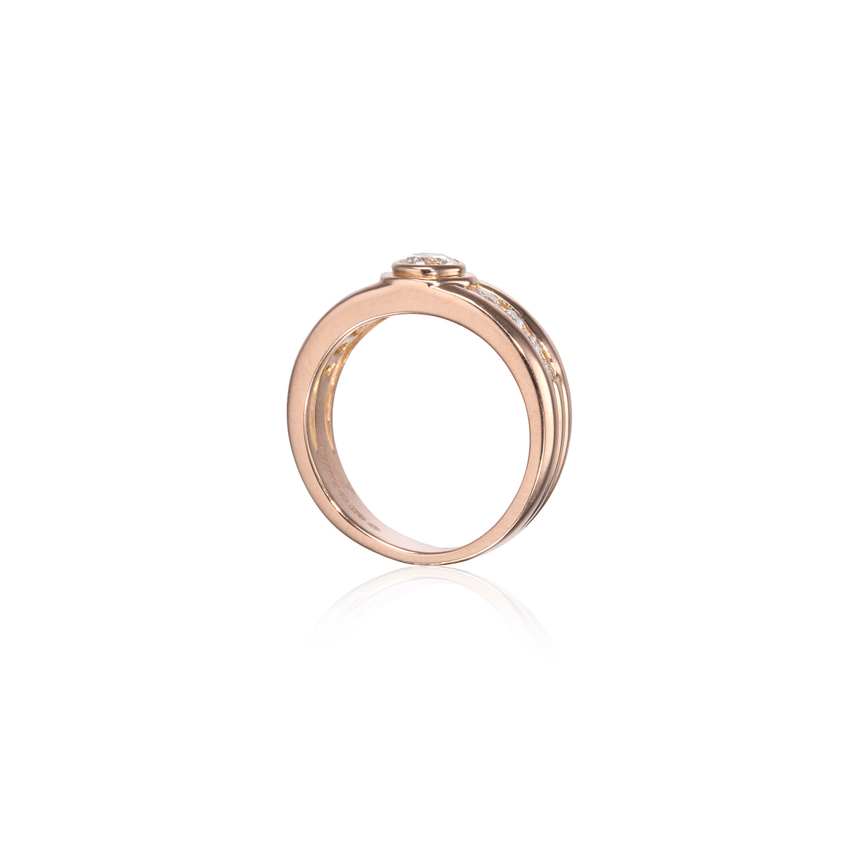 A rose gold ring with a small clear gemstone in a bezel setting, shown on a clean white background with a soft reflection below.