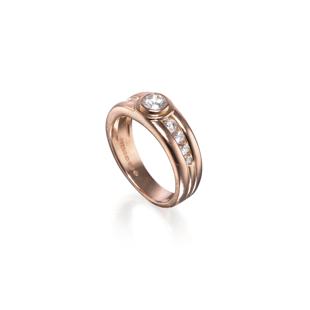 A rose gold ring with a round-cut center stone and a channel-set row of small clear stones, shown on a clean white background.