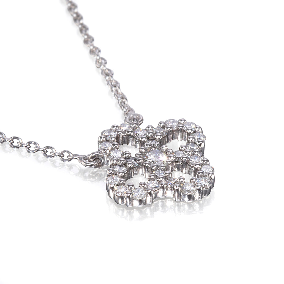 A white gold necklace with a four-leaf clover pendant encrusted with clear round gemstones, shown on a clean white background with a soft reflection.