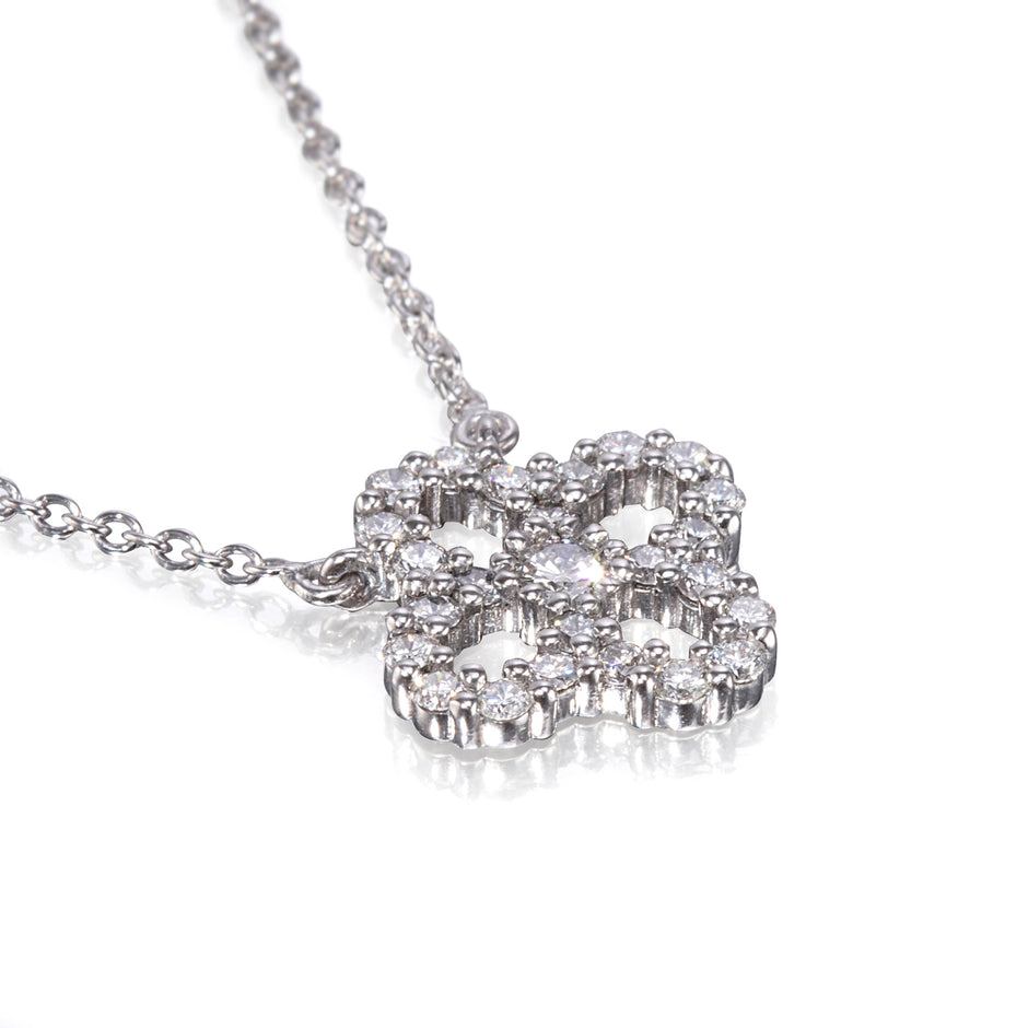 A white gold necklace with a four-leaf clover pendant encrusted with clear round gemstones, shown on a clean white background with a soft reflection.