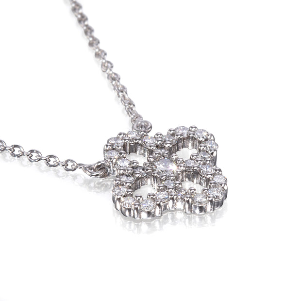A white gold necklace with a four-leaf clover pendant encrusted with clear round gemstones, shown on a clean white background with a soft reflection.