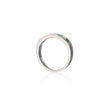 A white gold band ring featuring a row of small green gemstones on the front, displayed on a clean white background with a soft reflection below.