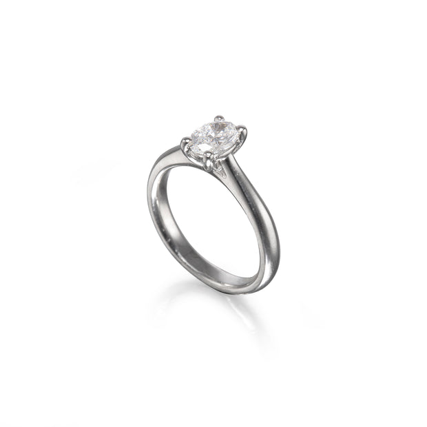 A platinum solitaire engagement ring with a round brilliant-cut diamond set in a four-prong setting, shown on a clean white background with a soft reflection.
