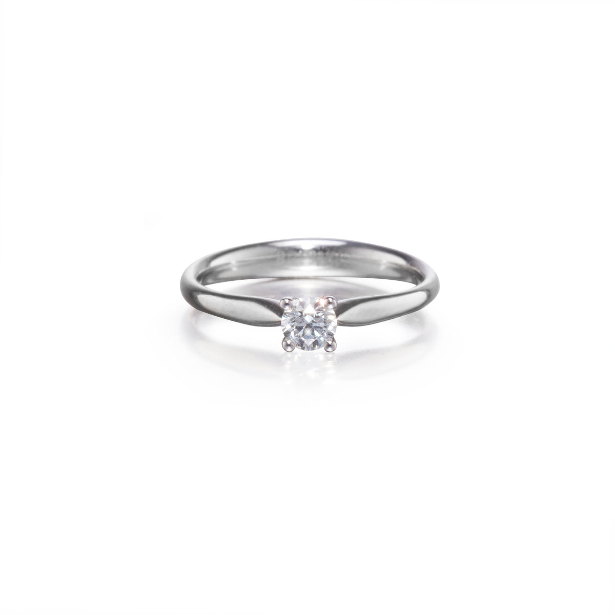 A platinum solitaire engagement ring with a clear round-cut gemstone, shown on a clean white background with a soft reflection.
