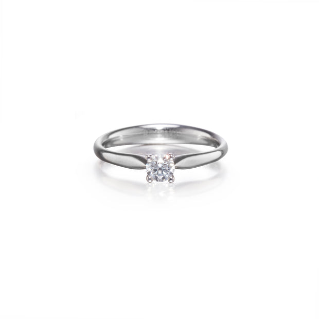 A platinum solitaire engagement ring with a clear round-cut gemstone, shown on a clean white background with a soft reflection.