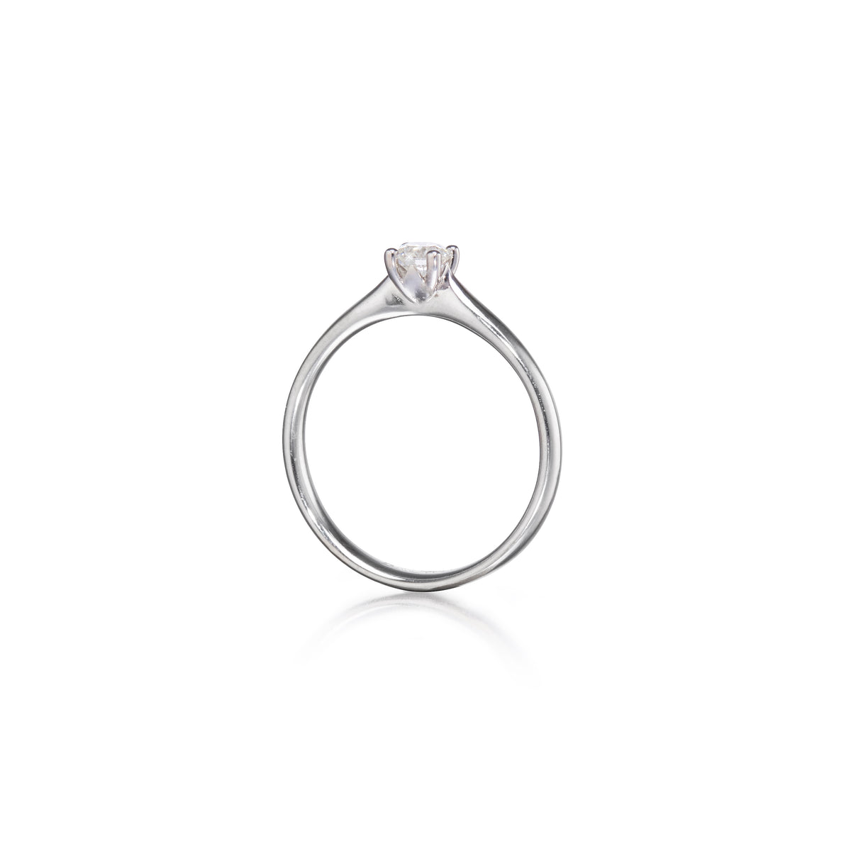 A platinum solitaire engagement ring with a heart-shaped clear gemstone, shown on a plain white background with a soft reflection below.