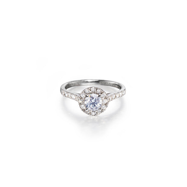 A platinum halo ring featuring a round-cut center stone surrounded by a double halo of smaller stones, set on a slim pavé band, photographed on a clean white background.