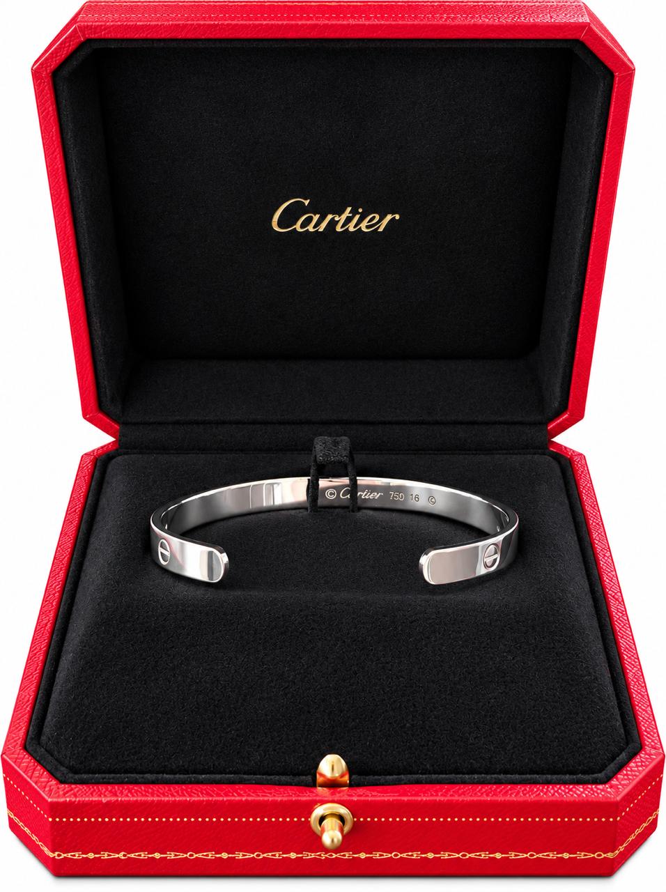 A white gold Cartier cuff bracelet displayed inside an open red Cartier presentation box with a black velvet interior and gold Cartier branding.