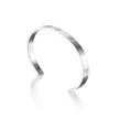 A white gold metal cuff bracelet with four evenly spaced screw-head details, photographed on a clean white background with a soft reflection.