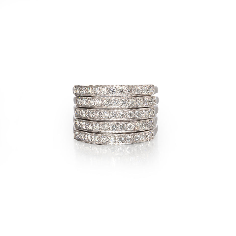 A stack of five slim diamond pave rings in a silver-toned metal, arranged vertically on a clean white background with a soft reflection below.