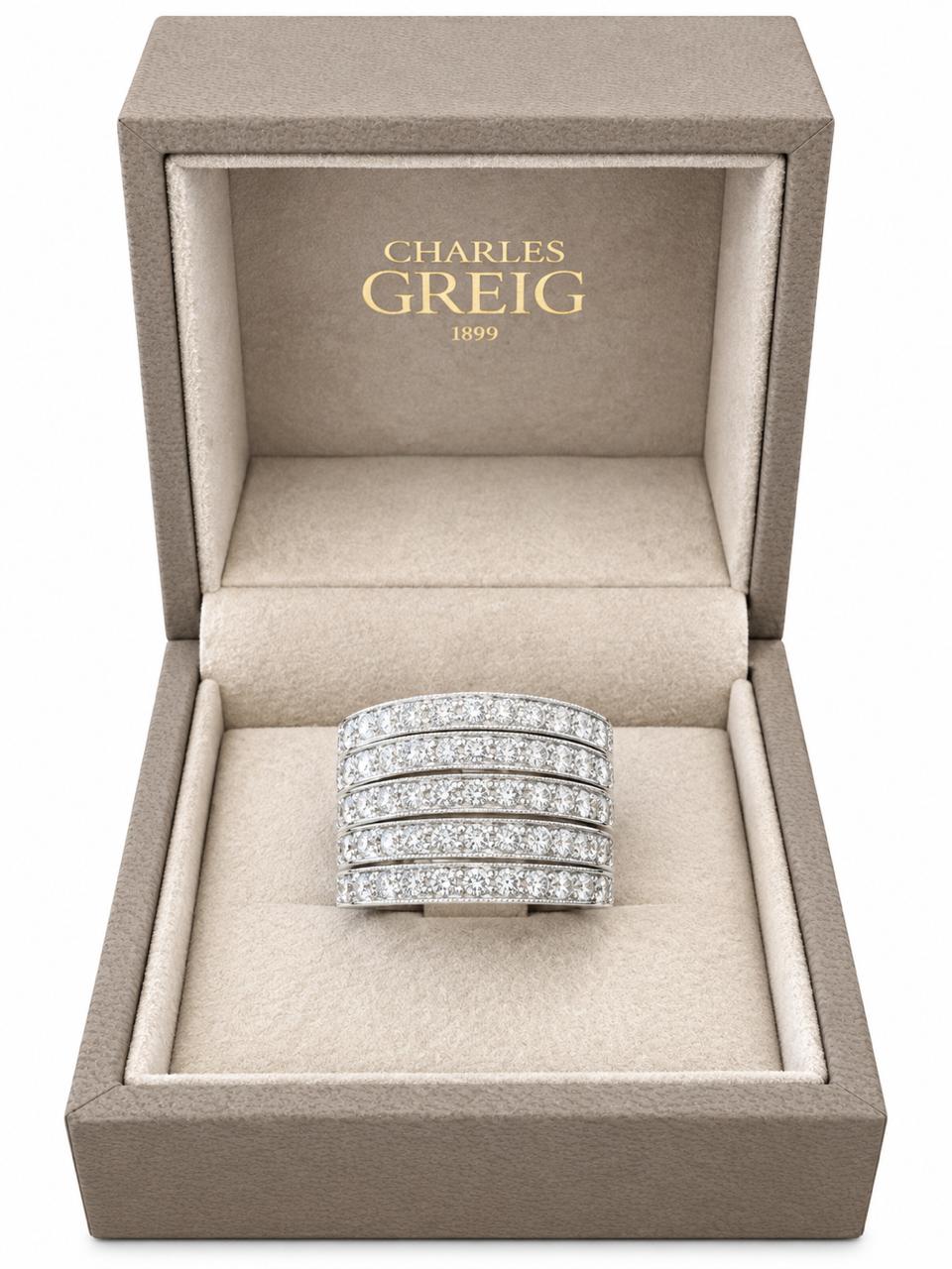 A multi-row diamond ring in a white gold band, presented inside an open Charles Greig jewelry box with a beige velvet interior.