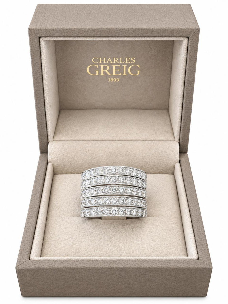 A multi-row diamond ring in a white gold band, presented inside an open Charles Greig jewelry box with a beige velvet interior.