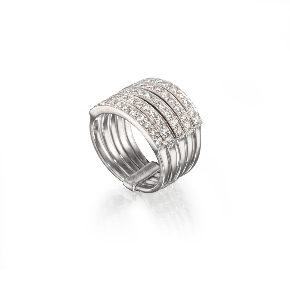 A white gold multi-band ring featuring rows of pavé-set clear stones on the upper band, photographed on a clean white background with a soft reflection below.