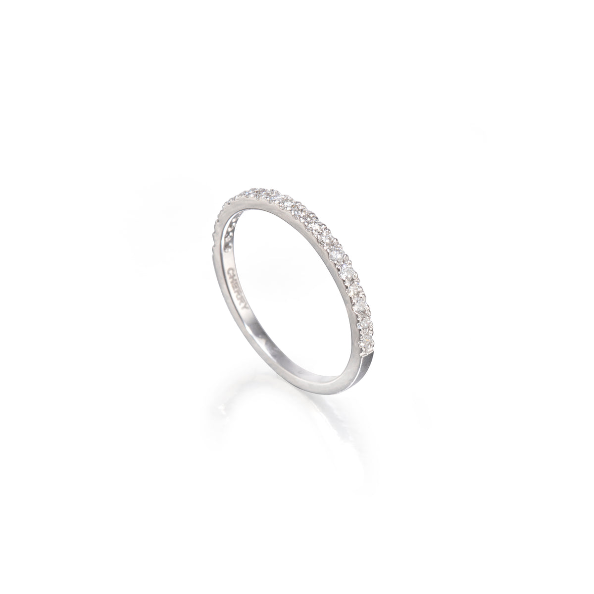 A white gold half-ring band featuring a single row of small clear pavé-set stones along the upper half, photographed on a clean white background with a soft reflection below.