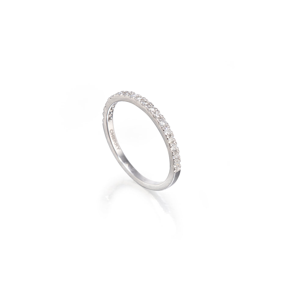 A white gold half-ring band featuring a single row of small clear pavé-set stones along the upper half, photographed on a clean white background with a soft reflection below.