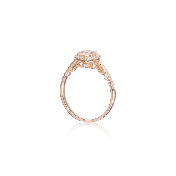A rose gold ring with a central oval clear gemstone and small accent stones, shown on a clean white background with a soft reflection below.
