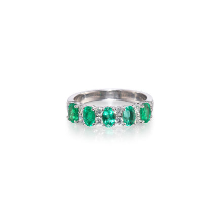 A white gold band ring featuring five oval-cut green emerald-cut gemstones, set against a plain white background with a soft reflection.