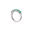 A white gold ring featuring a curved row of green emerald-cut gemstones, set against a clean white background with a subtle reflection.