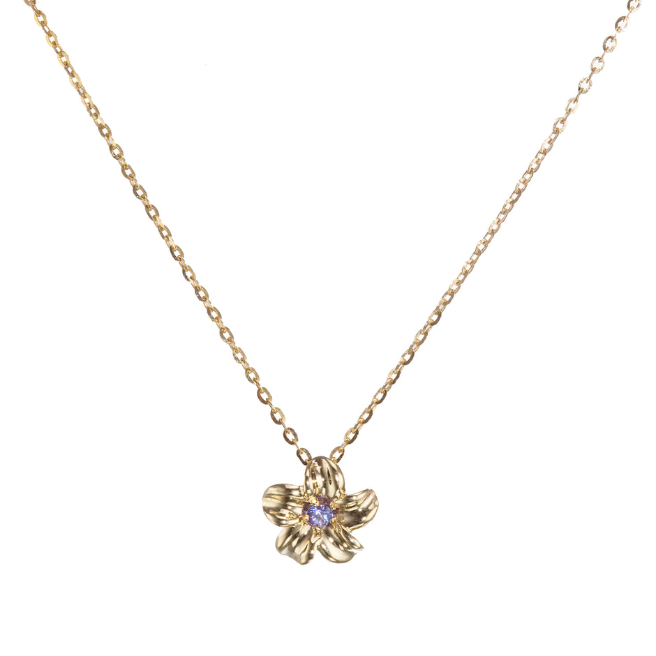 A delicate gold chain necklace featuring a small gold flower pendant with a tiny purple gemstone in the center, set against a plain white background.