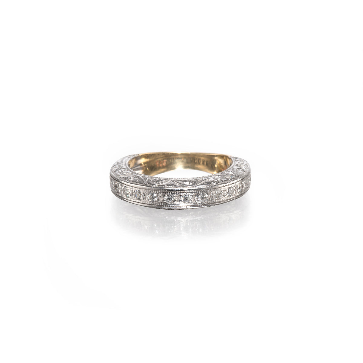A vintage-style diamond band ring with a yellow gold inner band and a white gold outer band paved with small clear stones, shown on a white background with a soft reflection.