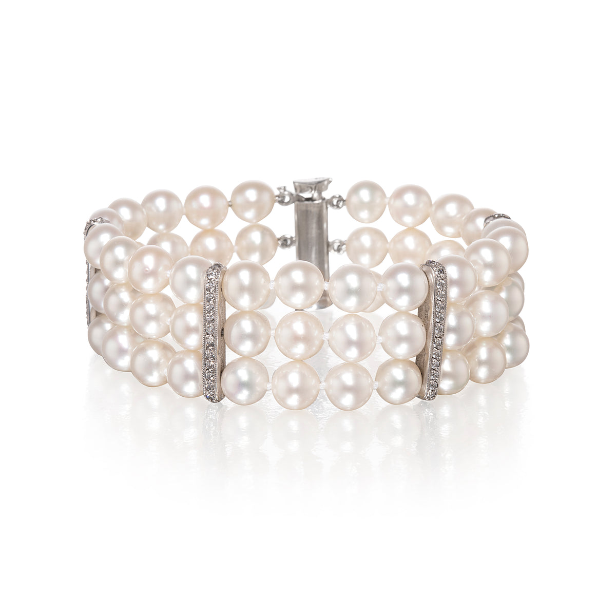 A multi-row pearl bracelet with white gold metal links and clear rhinestone accents, displayed on a clean white background with a soft reflection.
