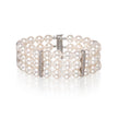 A multi-row pearl bracelet with white gold metal links and clear rhinestone accents, displayed on a clean white background with a soft reflection.