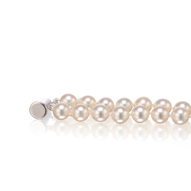 A strand of lustrous white with a polished silver-toned clasp, displayed horizontally on a clean white reflective surface.