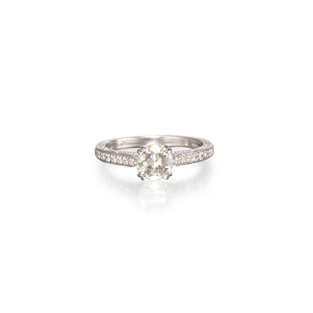 A Filigree diamond ring with a round-cut center stone and pavé-set side stones on a clean white background.