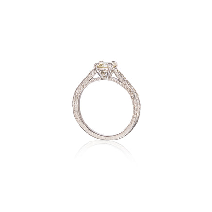 A Filigree diamond ring with a round-cut yellow center stone, shown from a top-down view on a white background with a soft reflection below.