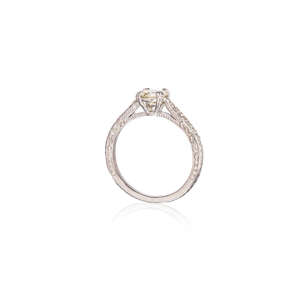 A Filigree diamond ring with a round-cut yellow center stone, shown from a top-down view on a white background with a soft reflection below.