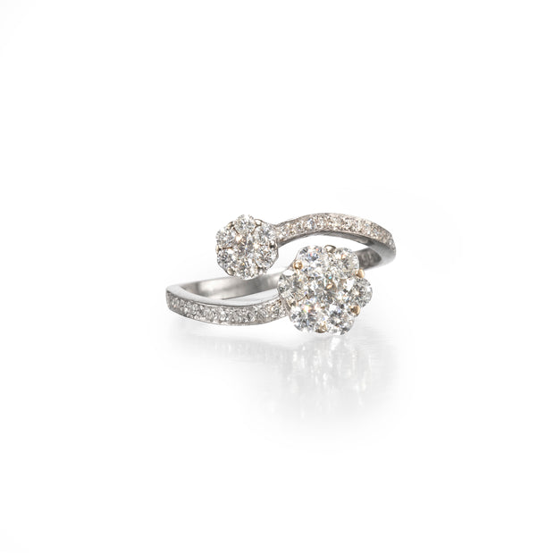 A platinum ring featuring a large round diamond cluster and a smaller matching cluster on a pavé-set band, photographed on a clean white background with a soft reflection.
