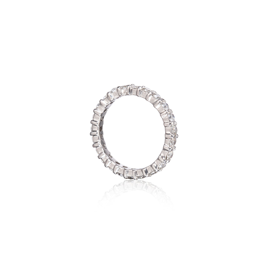 A platinum eternity ring set with round brilliant-cut diamonds, shown on a clean white background with a soft reflection below.