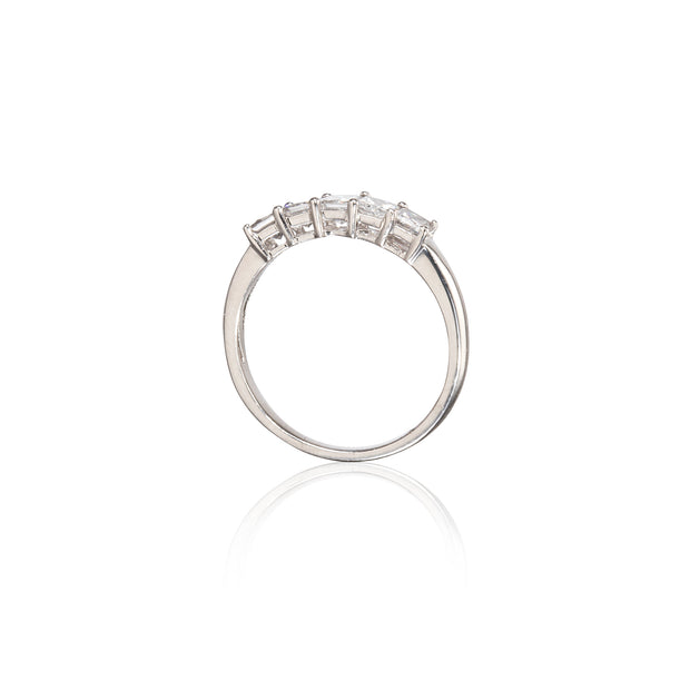 A platinum ring with a row of clear rectangular gemstones on the band, shown against a plain white background with a soft reflection below.