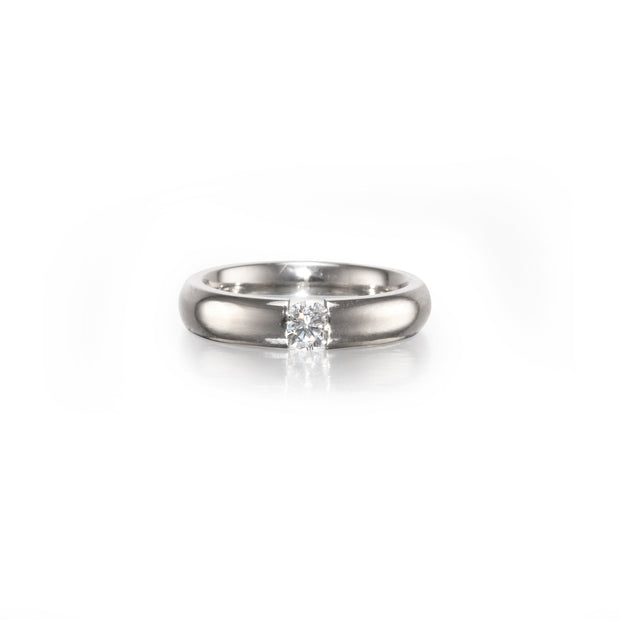 A classic solitaire engagement ring featuring a round brilliant-cut diamond set in a polished platinum band, centered on a clean white background with a soft reflection.