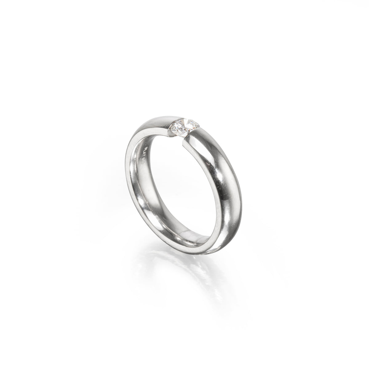 A polished platinum band ring with a single small clear gemstone set near the top, photographed on a clean white background with a soft reflection below