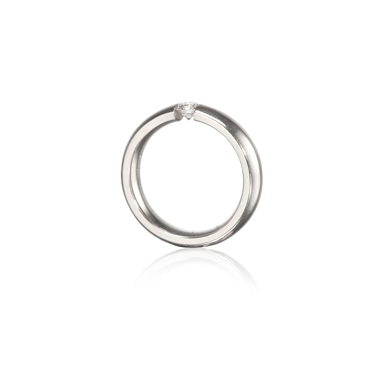 A polished platinum circular ring with a single small clear gemstone set at the top, shown on a clean white background with a soft reflection below.