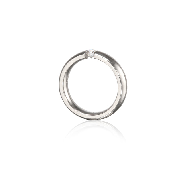 A polished platinum circular ring with a single small clear gemstone set at the top, shown on a clean white background with a soft reflection below.