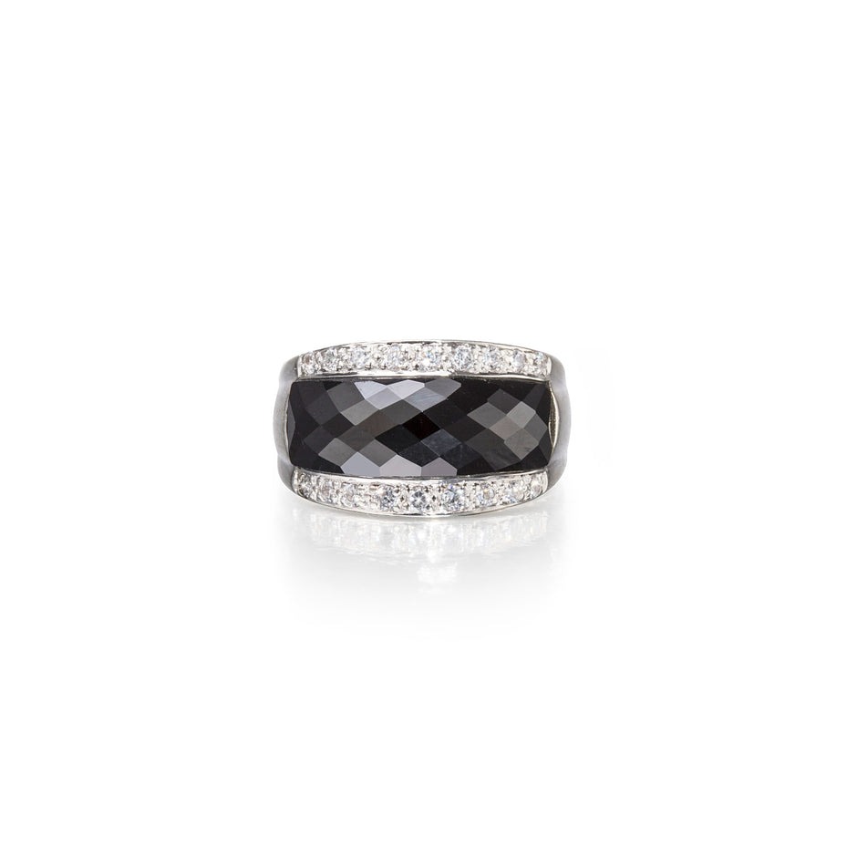 Ring with black gemstone and diamond-studded band on a white background