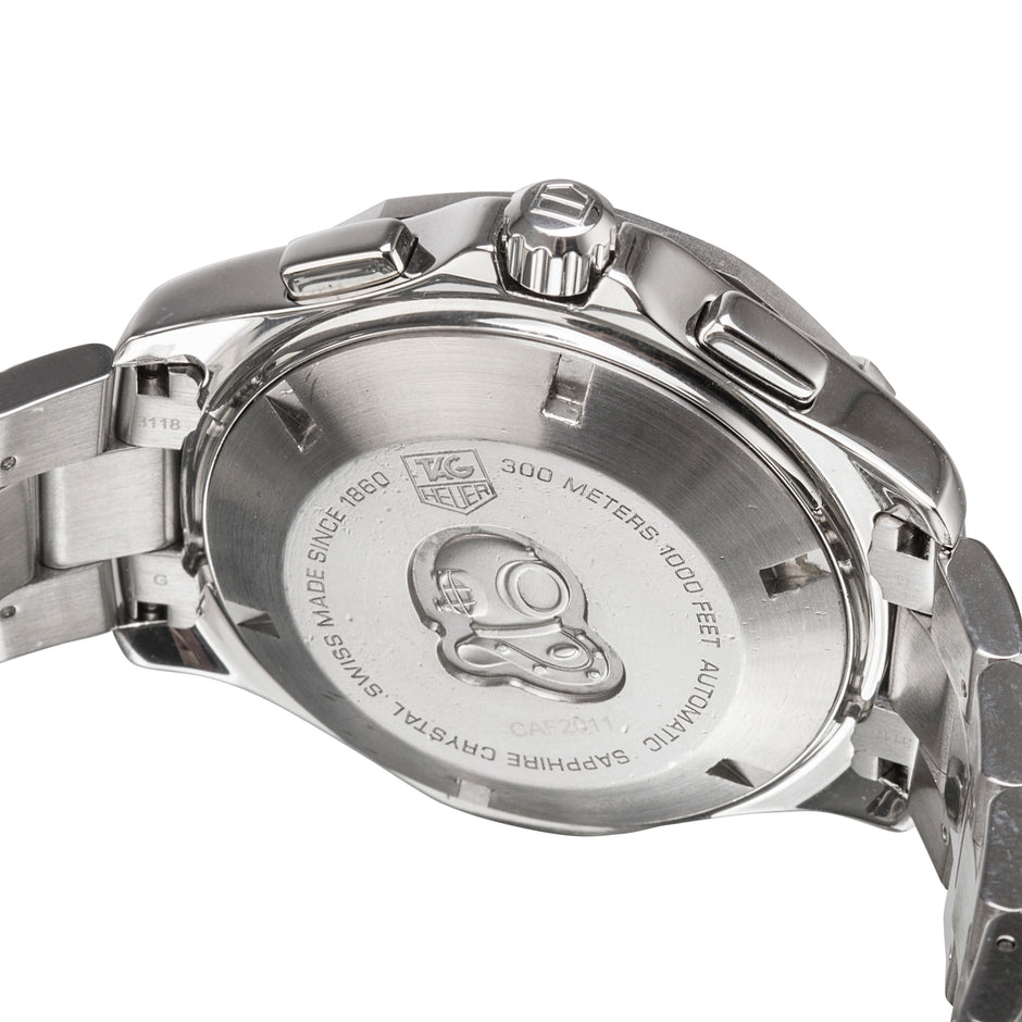 Close-up of the back case of a stainless steel wristwatch, showing engraved text and a logo mark on a clean white background.