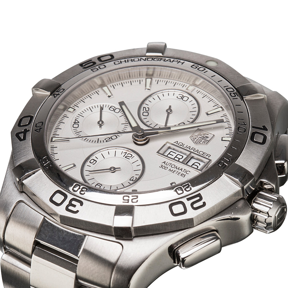 A close-up shot of a TAG Heuer Aquaracer automatic chronograph watch with a silver stainless steel case, white dial, and integrated link bracelet on a white background.