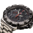 A close-up shot of a men's analog watch TAG, featuring a black dial with silver-tone hands, a red second hand, and a black bezel with white numerals, paired with a stainless steel link bracelet.
